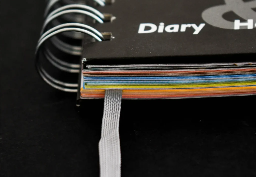 A wire-bound brochure featuring multiple different coloured paper stocks inside.