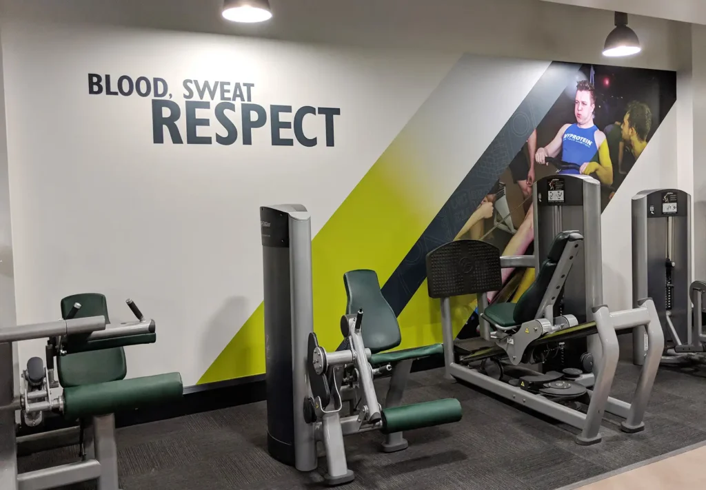 A gym wall wrapped with photography and an inspirational quote - Blood, sweat, respect.