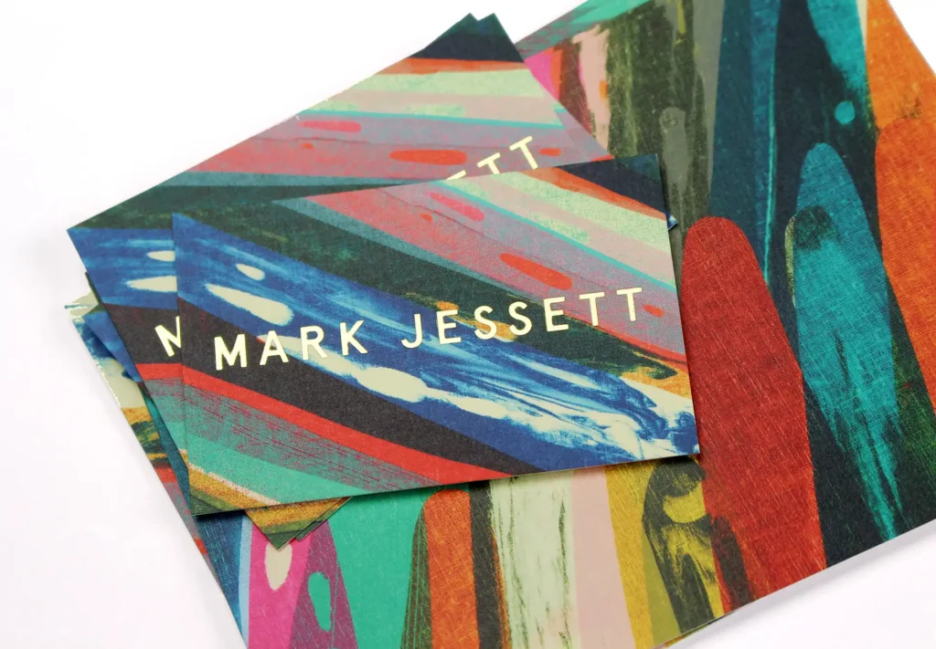 A custom-designed business card and postcard featuring vibrant colours in an artistic style, accentuated by gold foiling on the company logo.