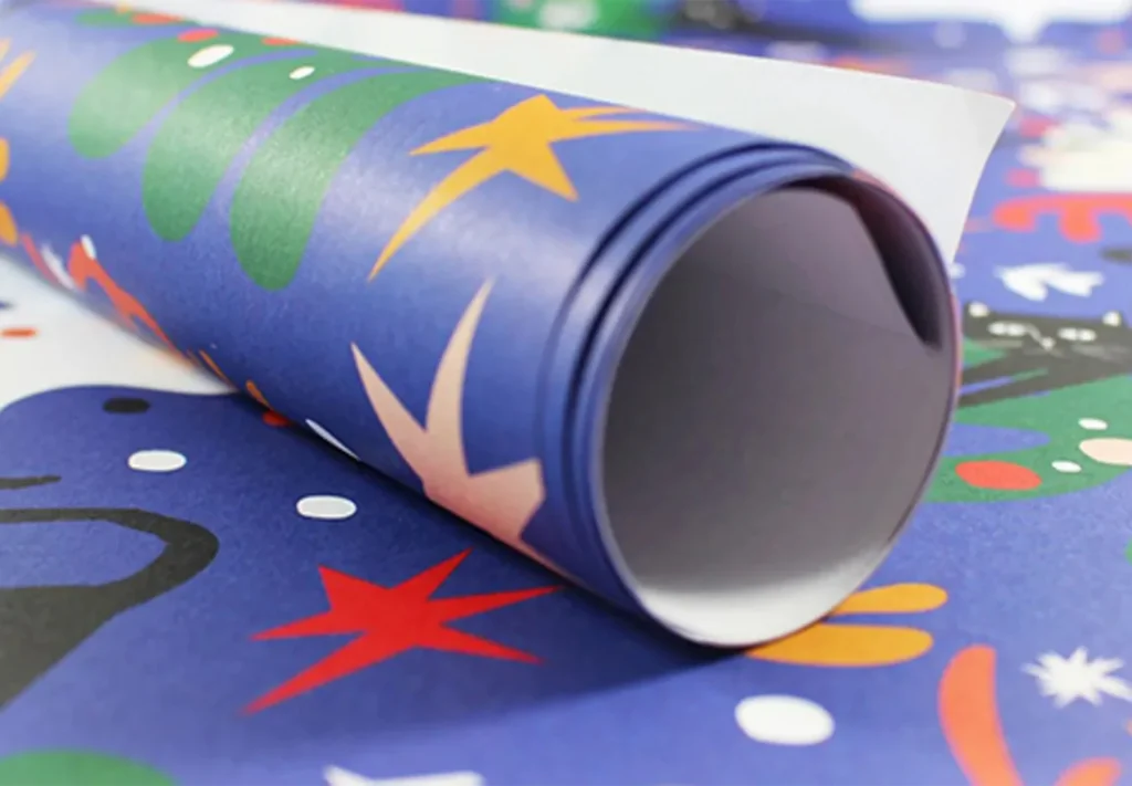 A roll of Christmas wrapping paper adorned with illustrations of cats and festive shapes.