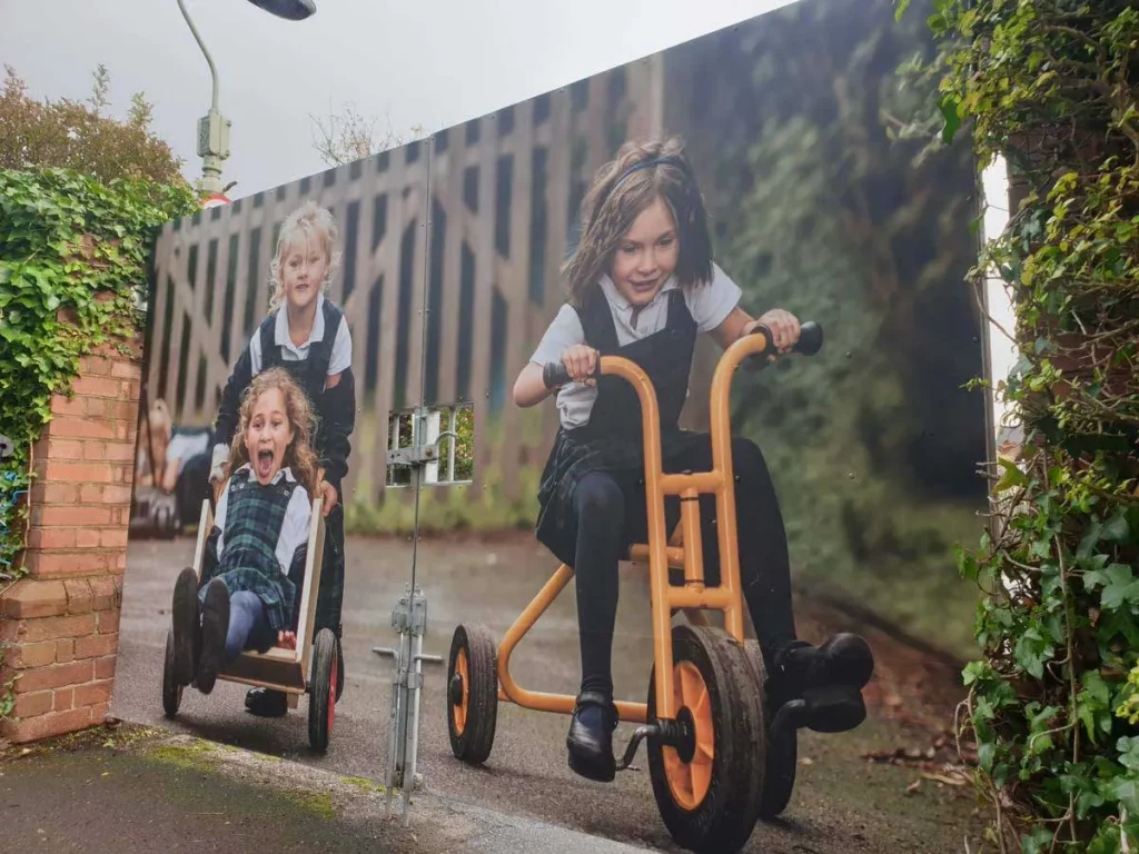 A school gate wrapped in a large image of the pupils.