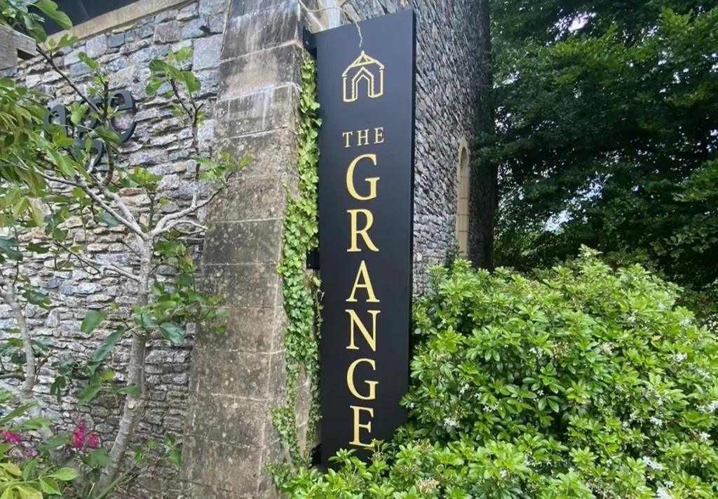 A large sign affixed to an old stone wall, prominently displaying the name and branding of the company