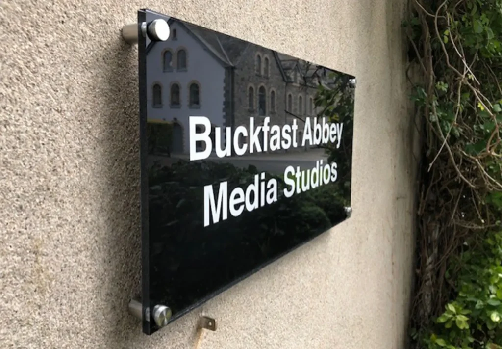 An acrylic sign positioned to inform passersby of the company located inside the building.