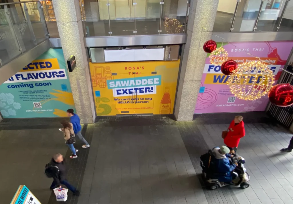 Bright, colourful hoarding boards installed in front of a shop under renovation, printed to capture attention and create excitement for the upcoming restaurant opening.