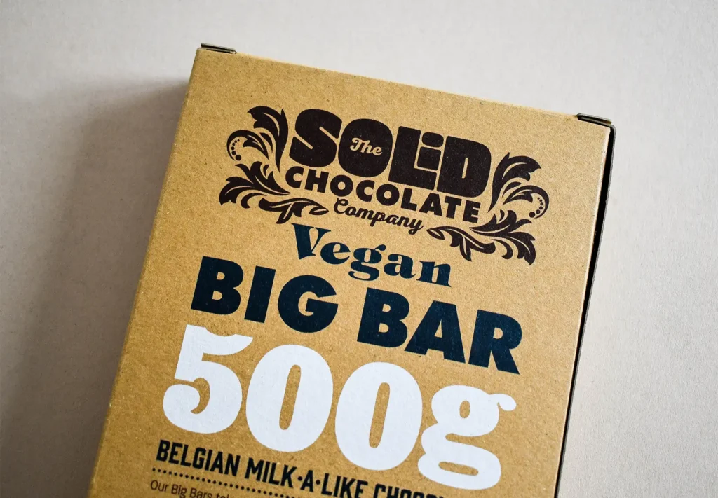 A close-up photograph showcasing the branding on the front of custom chocolate bar packaging, highlighting the exceptional print detail achieved on kraft card.