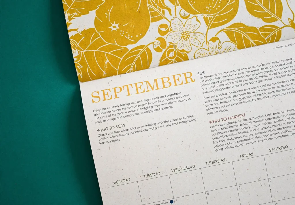 Close-up of the September page in a stitch-bound calendar, featuring intricate nature-inspired linocut illustrations.